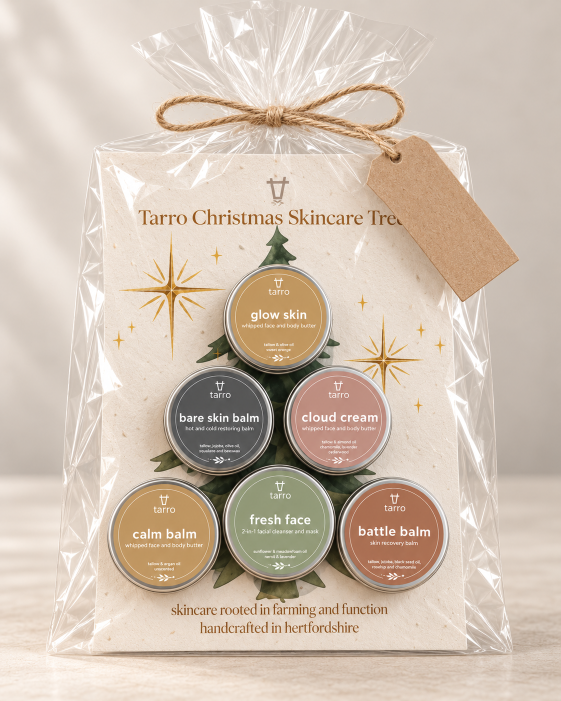 A Taro Christmas 
Skincare Tree gift set in clear cellophane packaging with a kraft paper hang tag, showing six small round skincare tins arranged in a tree shape on a cream card.