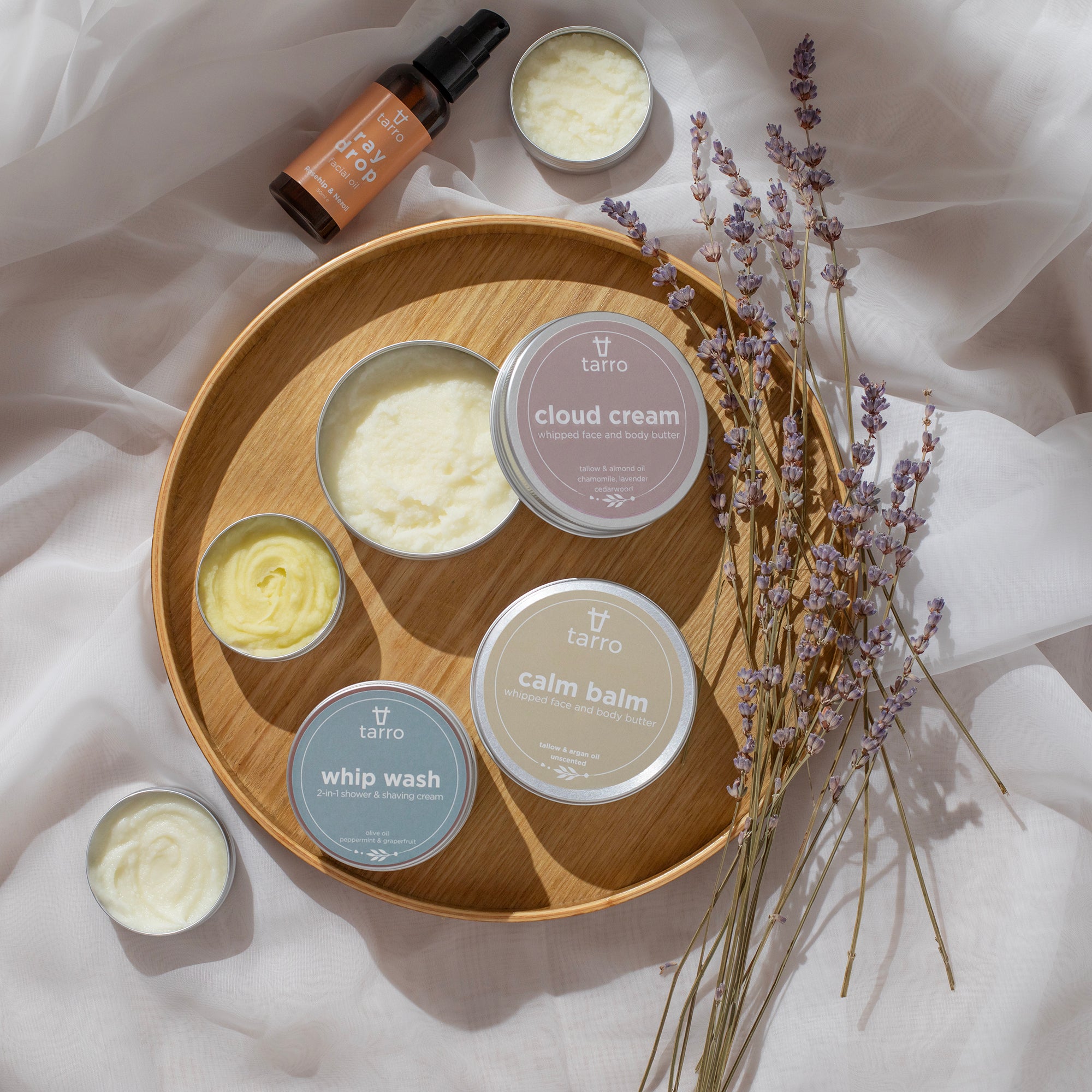 Collection of Tarro skincare products on a wooden tray with lavender flowers.